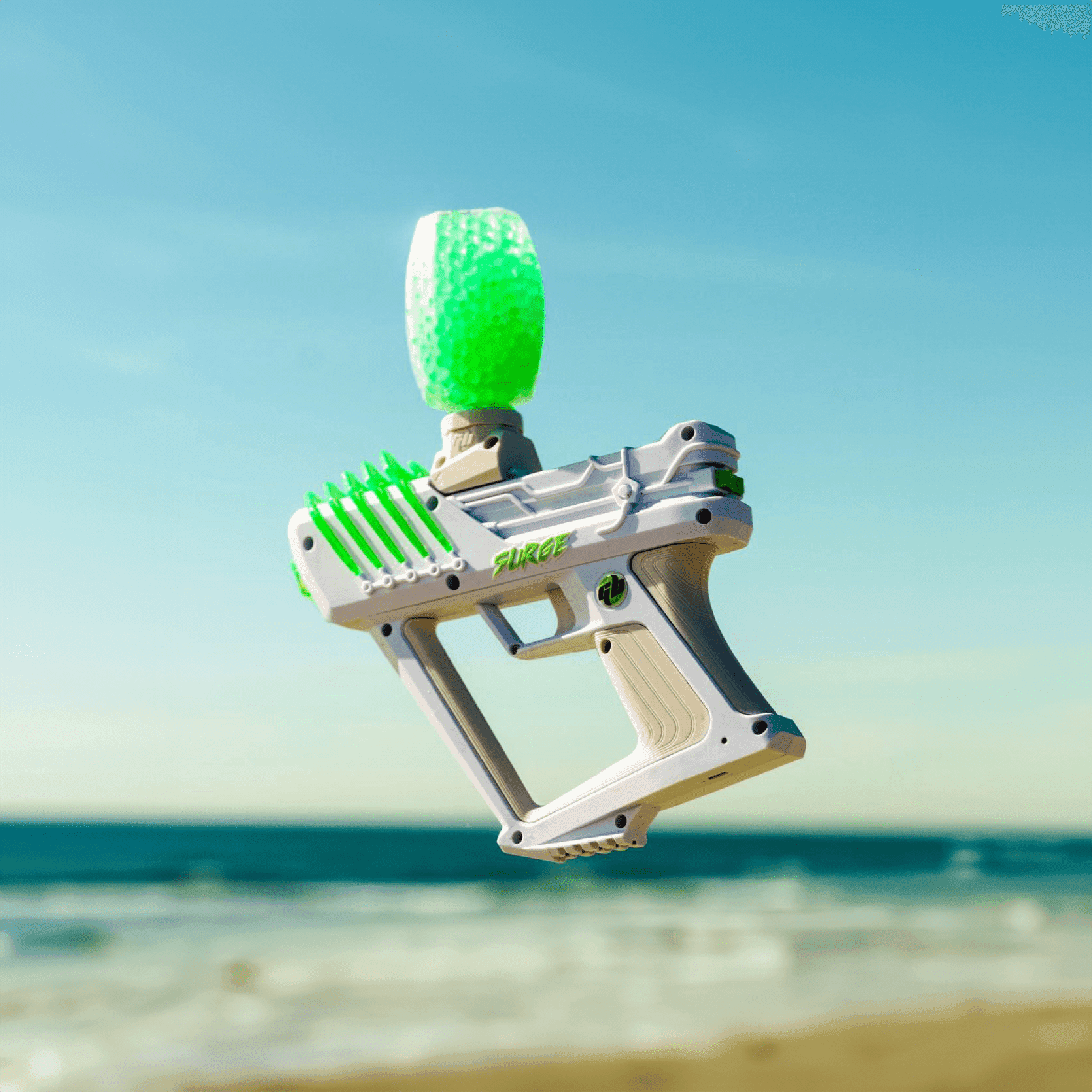 Bijeli Gel Blaster Surge marker sa spremnikom zelenih gel kuglica, snimljen uz more